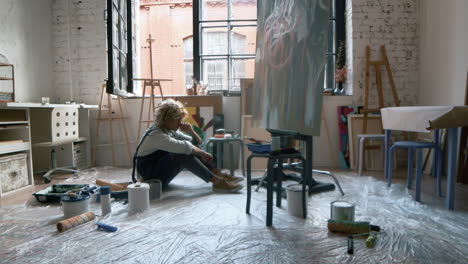 artista sentado frente a la pintura
