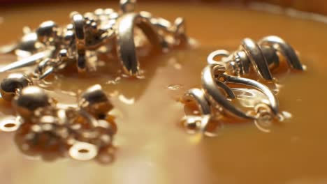 glistening gold jewelry nested in shimmering liquid: captivating close-up shots of exquisite accessories in a rich, glossy environment