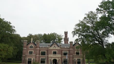 Tilting-down-from-cloudy-sky-while-flying-towards-Schaffelaar-Castle-in-Barneveld,-the-Netherlands