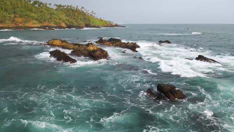 drone flying over indian ocean rocks in sri lanka at sunset