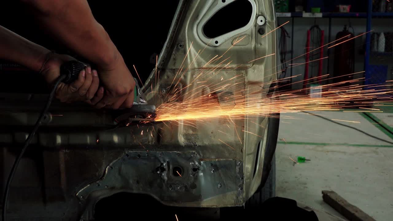 Worker using electric grinder machine cutting steel. Steel cutting machine in auto body repair shop