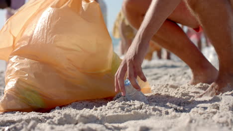 Diversos-Voluntarios-Recogen-Basura-En-Una-Playa-De-Arena,-Con-Espacio-Para-Copiar