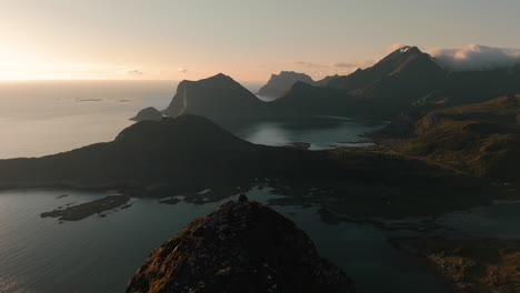 Offersøykammen-in-Lofoten-Norway-aerial-view-at-sunset,-couple-sitting-on-summit