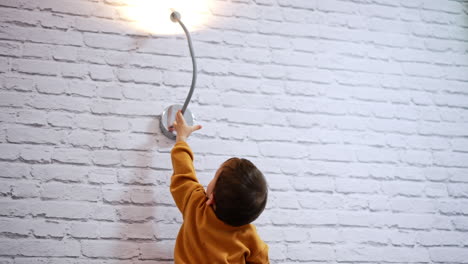 child reaching for wall lamp