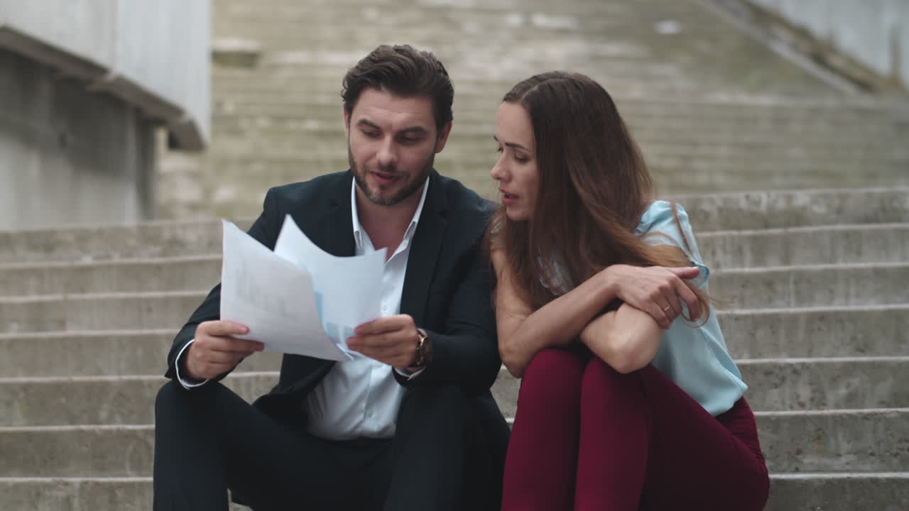 trabajadores sentados en las escaleras al aire libre. personas discutiendo documentos en la calle de la ciudad