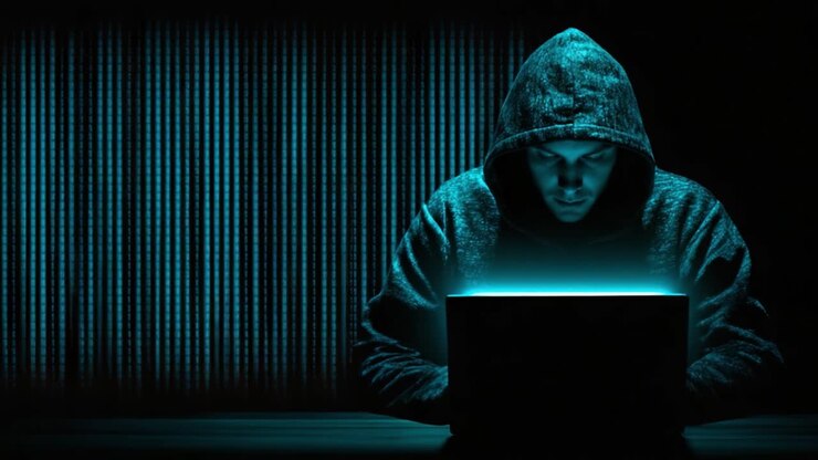 Una Figura Misteriosa Immersa in Oscure Attività Cyber, Circondata da Codice Luminoso, che Illumina le Sue Intenzioni Dietro un Abito Incappucciato e un Portatile Aperto
