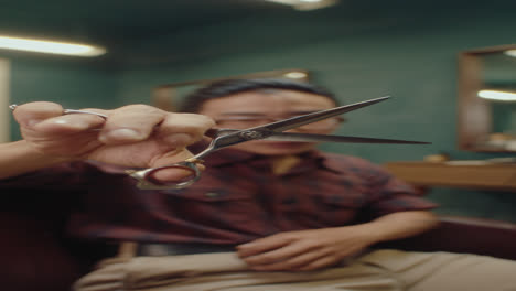 barber showing hairdressing scissors on camera