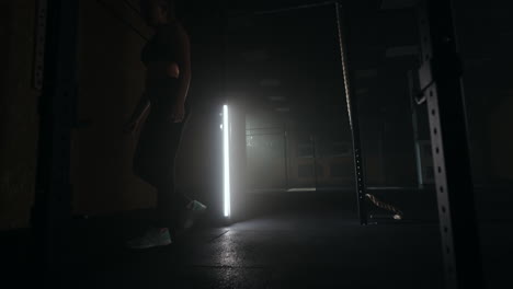 a strong young athletic woman goes upside down on her hands in the gym. a woman is fit on her hands in a dark gym. training at least upside down