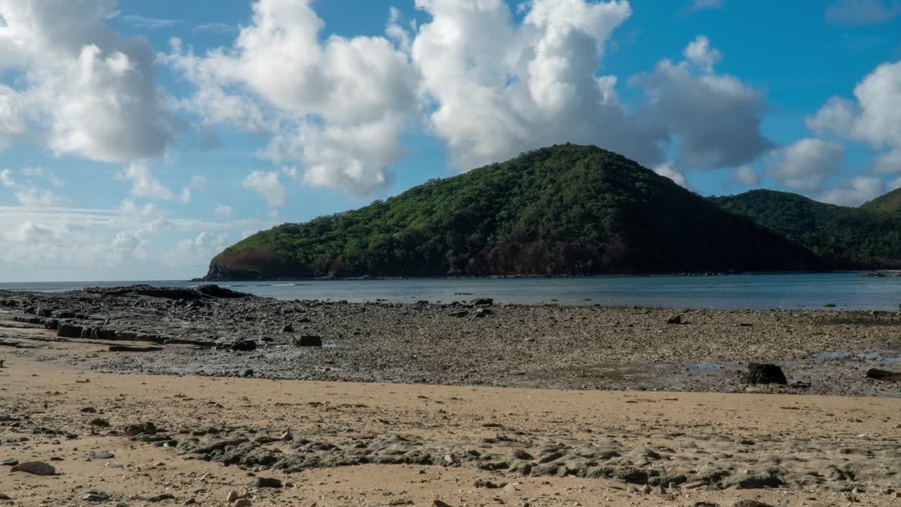 marea que cae en la pequeña bahía de la isla tropical con la colina de la selva en fiji, nubes rodando, lapso de tiempo