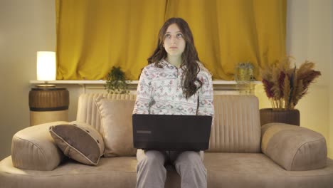 una joven infeliz usando una computadora portátil por la noche. no está de buen humor.