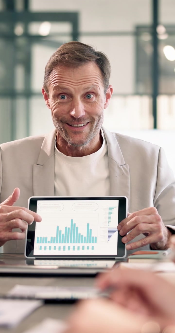 Uomo d'affari maturo che presenta dati finanziari su tablet durante una riunione in ufficio