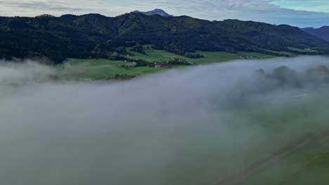 austrian countryside in the alps with fog in the valley - aerial reveal