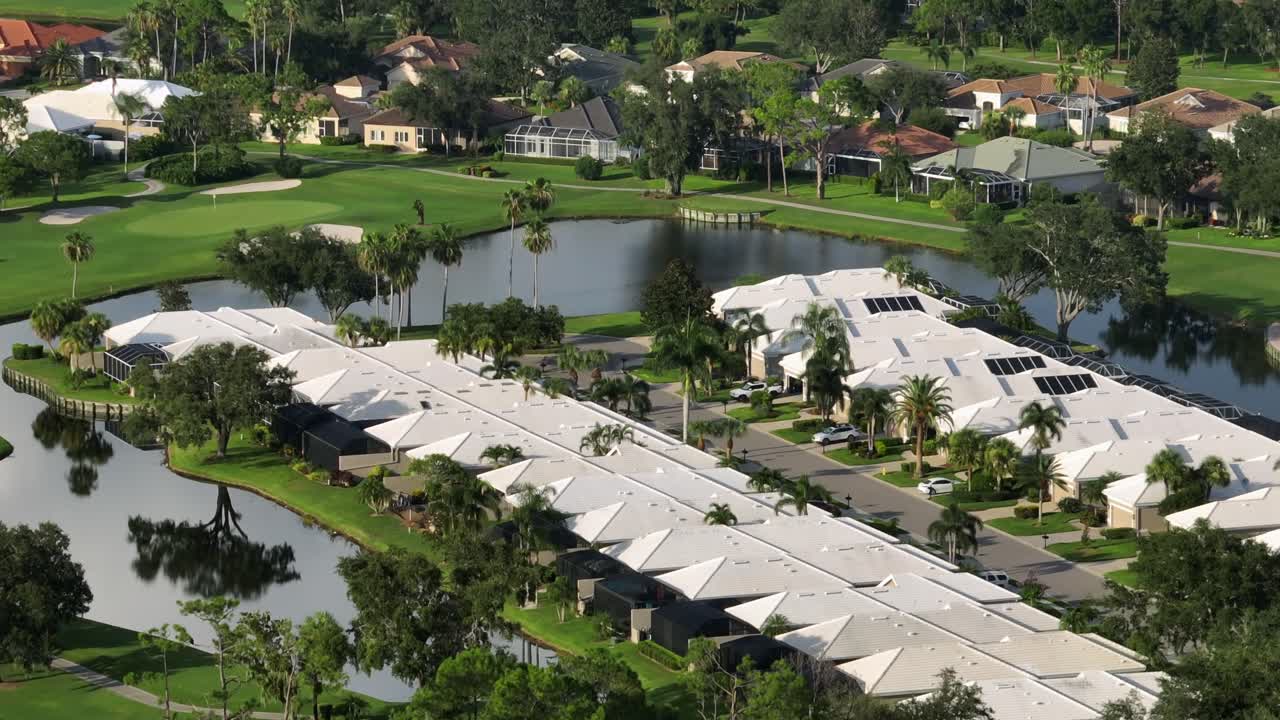 Exclusive noble homes in golf course club of Florida. Sunset time in USA. Aerial wide shot. Private lake and ponds inside quiet neighborhood. Upscale high class buildings