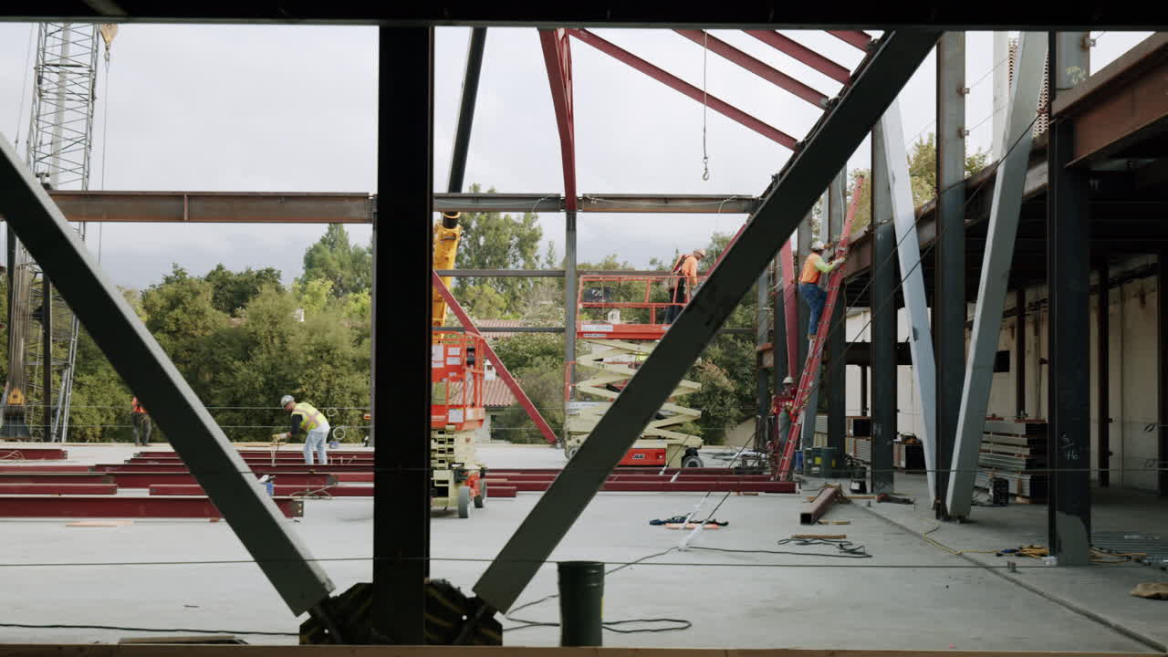 Construction site with workers, steel beams, and heavy equipment