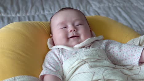 infant baby smile on camera, baby laughing while lying on yellow bed