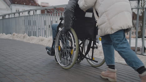 disabled person in wheelchair taking a stroll with his friend around the city in winter