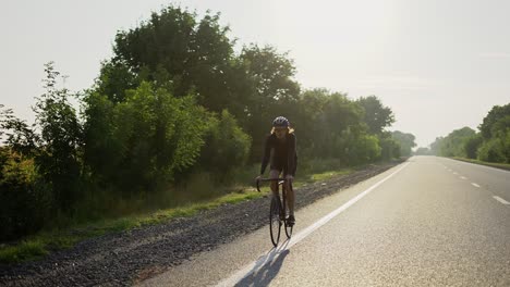 male cyclist in helmet rides bicycle along an empty track