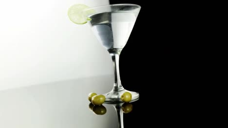 Chevron-Musterdesign-über-Cocktailglas-Mit-Limettenkeil-Vor-Schwarzem-Hintergrund