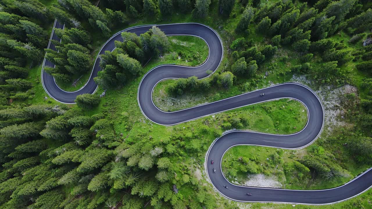 Top-down aerial view of winding mountain road weaving, lush green landscapes
