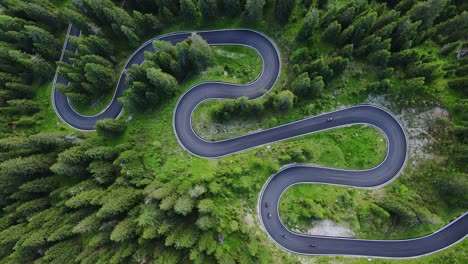 Top-down aerial view of winding mountain road weaving, lush green landscapes