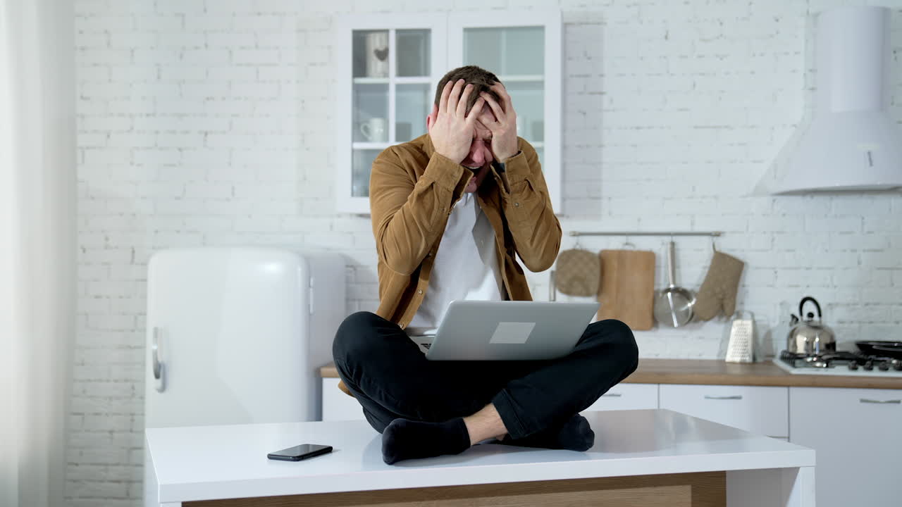 Man typing on laptop. Crazy man using laptop sitting on the table at home