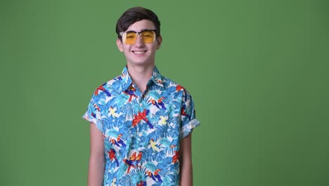 young handsome iranian teenage boy ready for vacation against green background