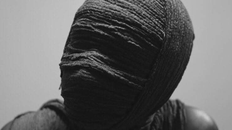 Una mummia di donna su uno sfondo bianco alza la testa