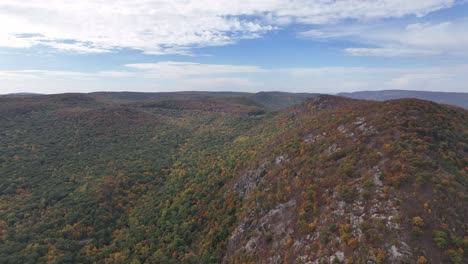 an aerial view high over storm king mountain in upstate ny during the fall, on a beautiful day with white clouds