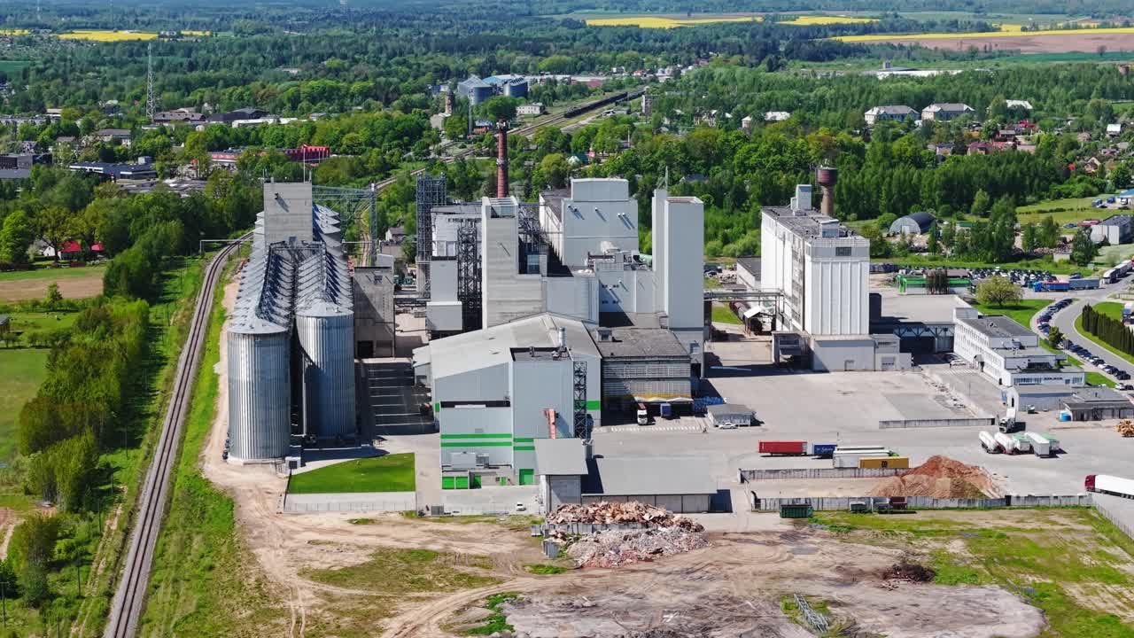 High aerial view of industrial factory complex surrounded by green fields and trees