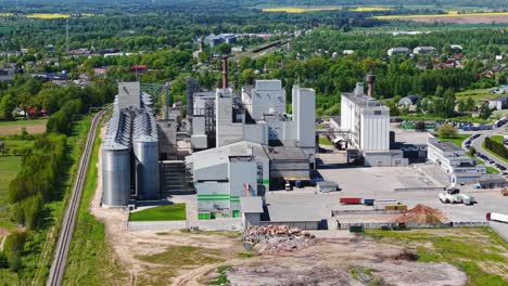 high aerial view of industrial factory complex surrounded by green fields and trees