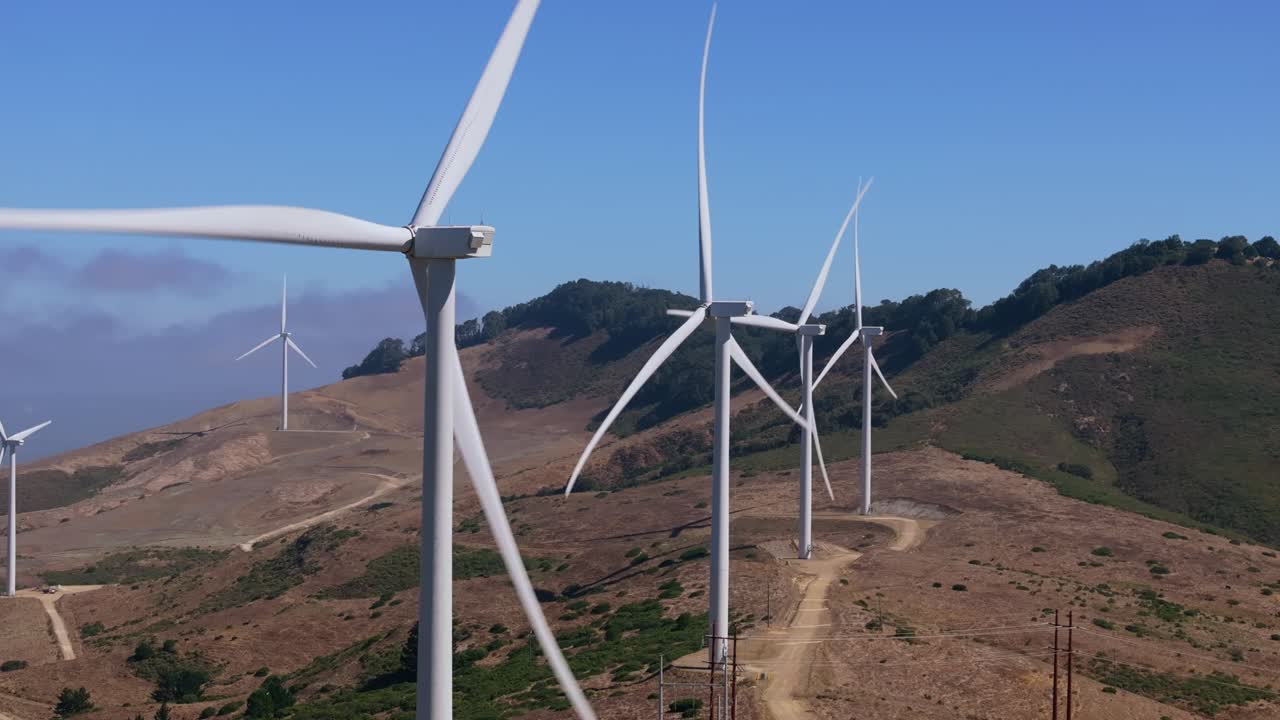 Wind turbines spin on California hills under blue sky