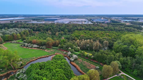lush green park with a narrow river. large storehouses at backdrop. picturesque countryside of the netherlands. top view.