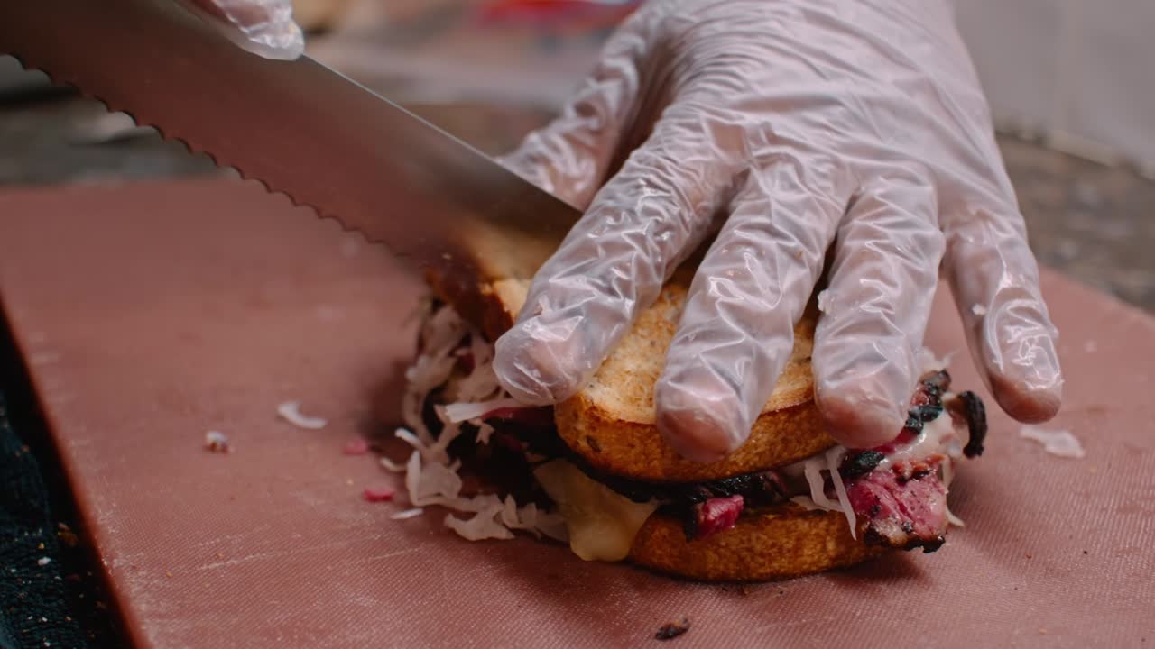 sándwich de pastrami de corte con las manos en guantes, tiro medio
