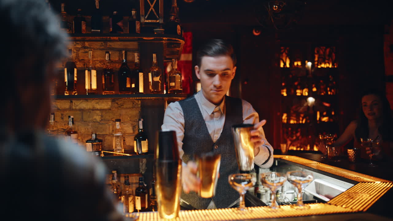 Nahaufnahme eines erfahrenen Barkeepers, der nachts in einem Luxusrestaurant mit einem Shaker arbeitet