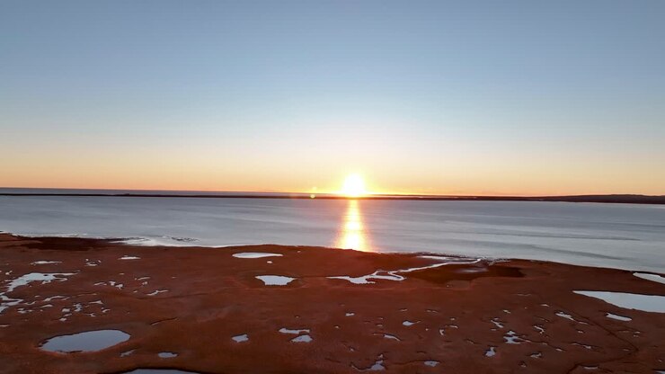 Lindo pôr do sol refletindo na água calma do oceano no sul da Islândia durante a maré baixa
