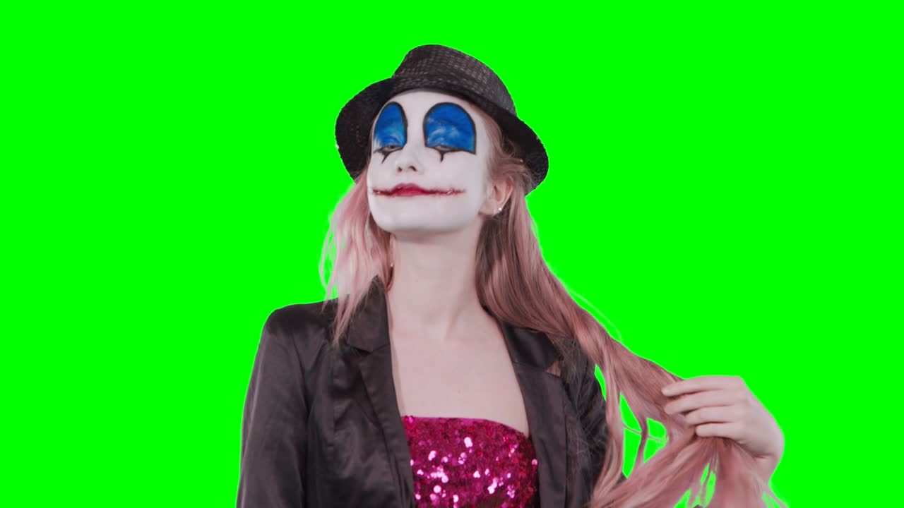 The girl clown is playing with hair laughing at the camera.