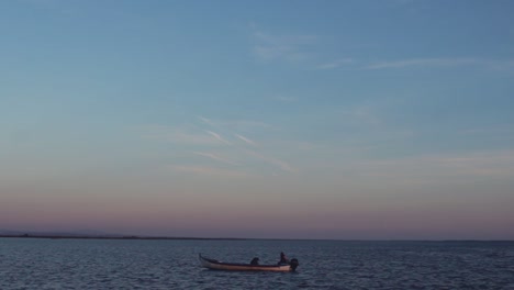 single fishing boat passing by the horizon