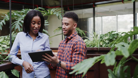 happy diverse male and female colleagues using tablet talking in office foyer, copy space