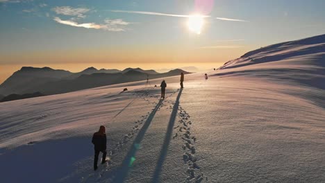 Una-Toma-Cinematográfica-Con-Un-Dron-De-Tres-Amigos-Caminando-En-La-Cima-Del-Mundo-Hacia-El-Sol