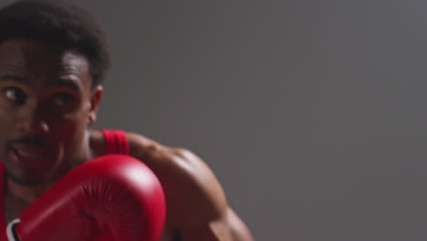 Close-Up-Studio-POV-Shot-Of-Tattooed-Male-Boxer-Wearing-Boxing-Gloves-In-Boxing-Match-Punching-Towards-Camera-1