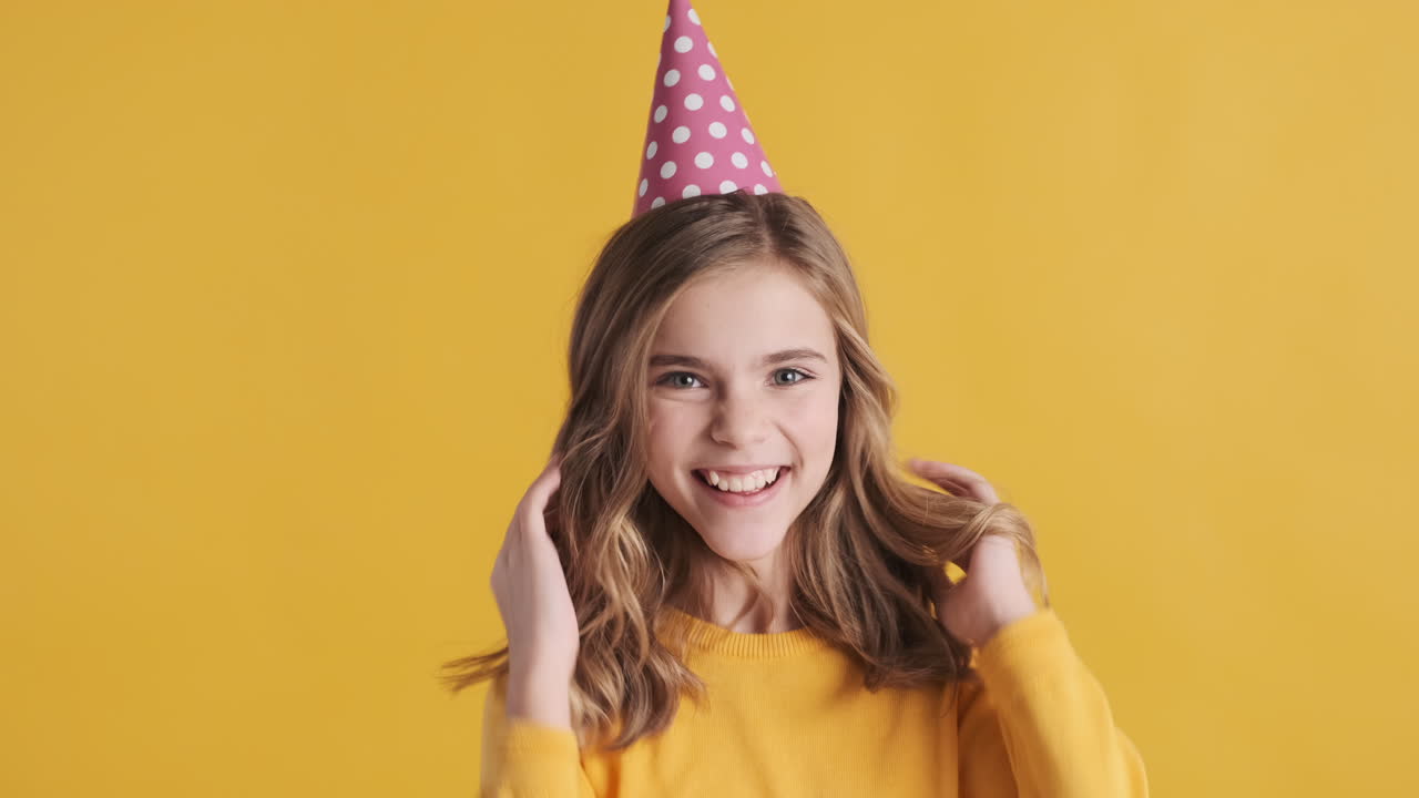 una adolescente caucásica con un sombrero de fiesta y saltando.