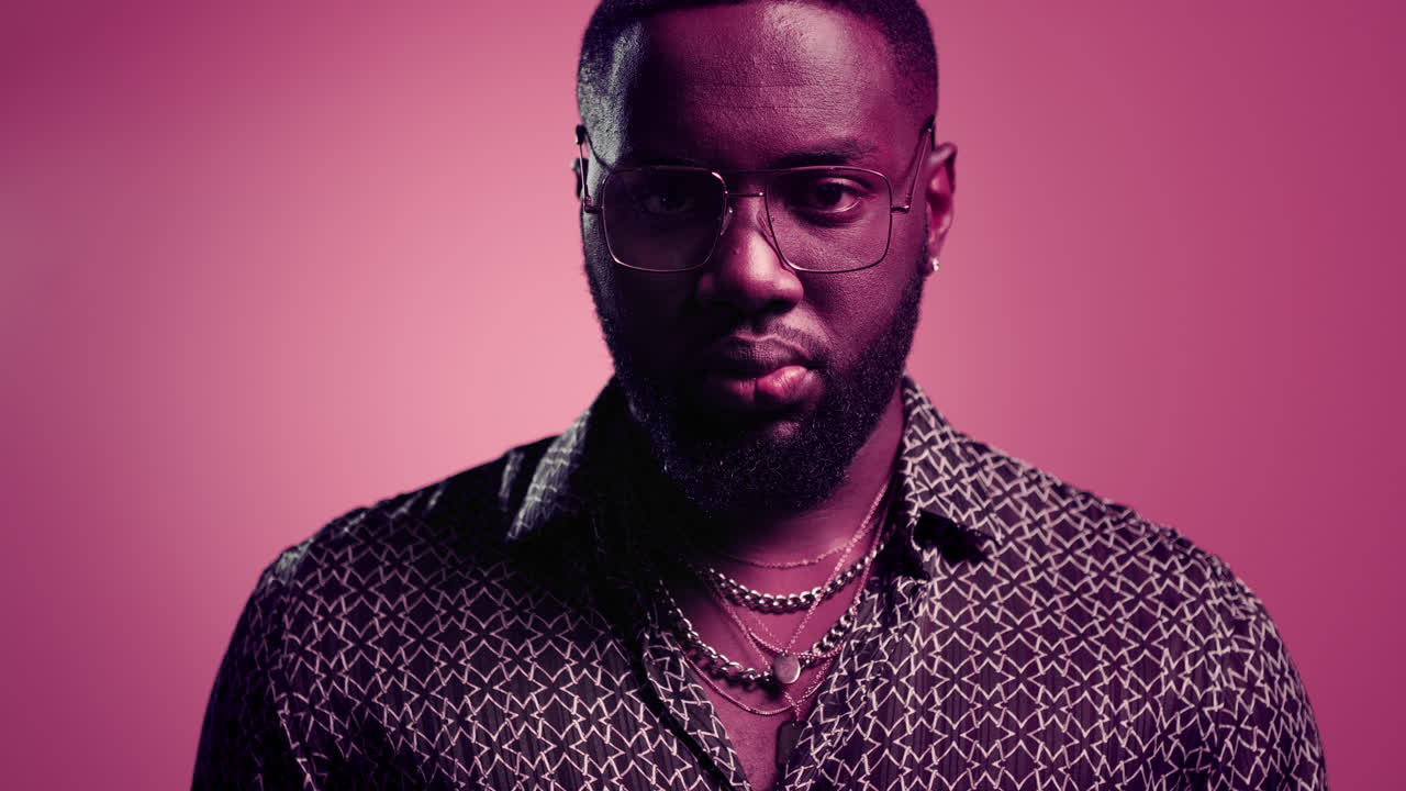 아프리카계 미국인 남자가 스튜디오에서 렌즈를 쳐다보고 있다. 아프로 남자가 실내에서 머리를 들고 있다.