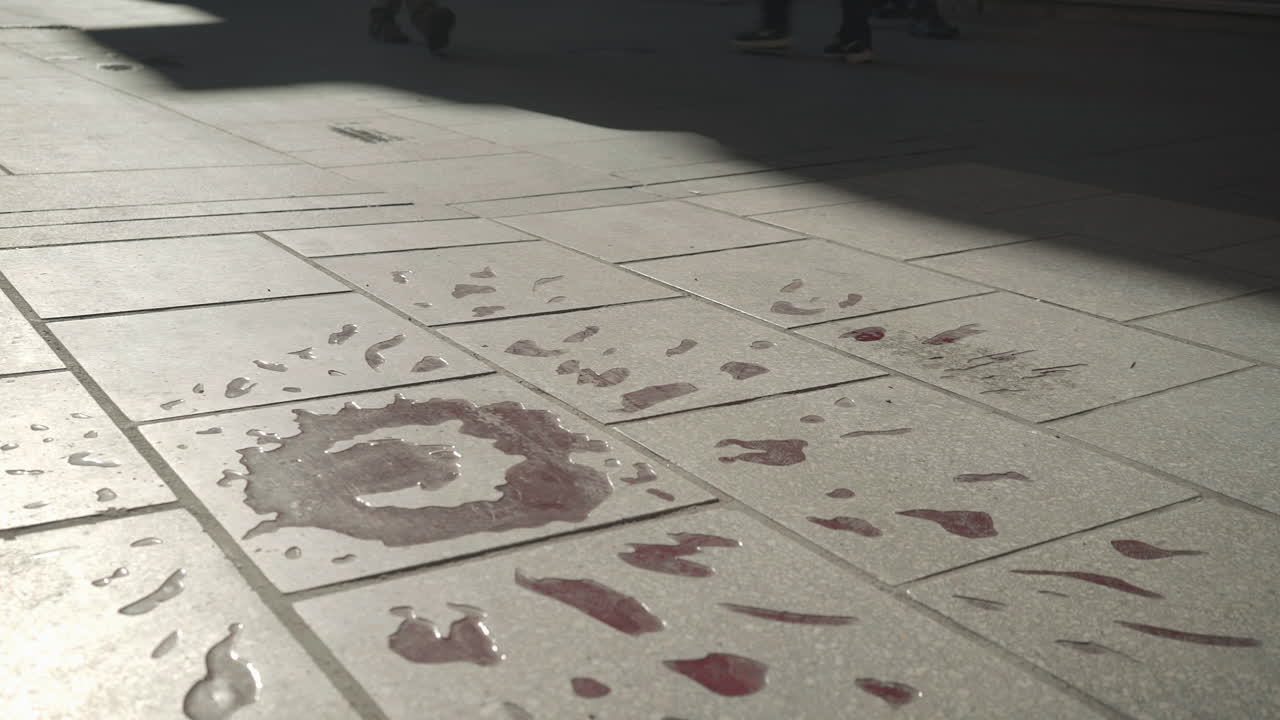 Wide view of a group walking by a Sarajevo rose, a war memorial on the street indicating where three or more people were killed during the siege of Sarajevo, Bosnia.