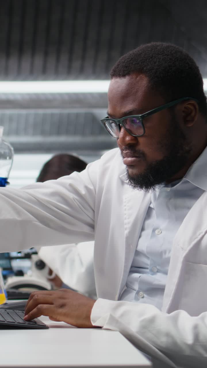 Vertical video Medical technician investigates chemical sample properties using PC software