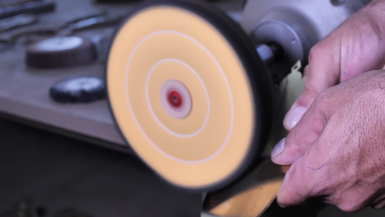 작업장에서 회전식 그라인더로 작은 부품을 연마하는 장인의 손