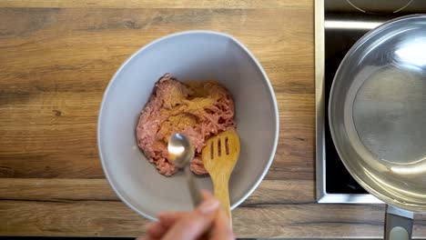 Mujer-Agregando-Una-Cuchara-De-Especias-A-Un-Tazón-De-Carne-Picada-En-Cámara-Lenta