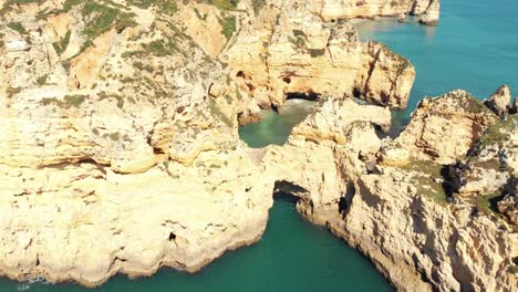 Ponta-da-Piedade-Lighthouse,-aerial-approaching-cliff-formations-along-coastline-of-Lagos,-Algarve,-Portugal