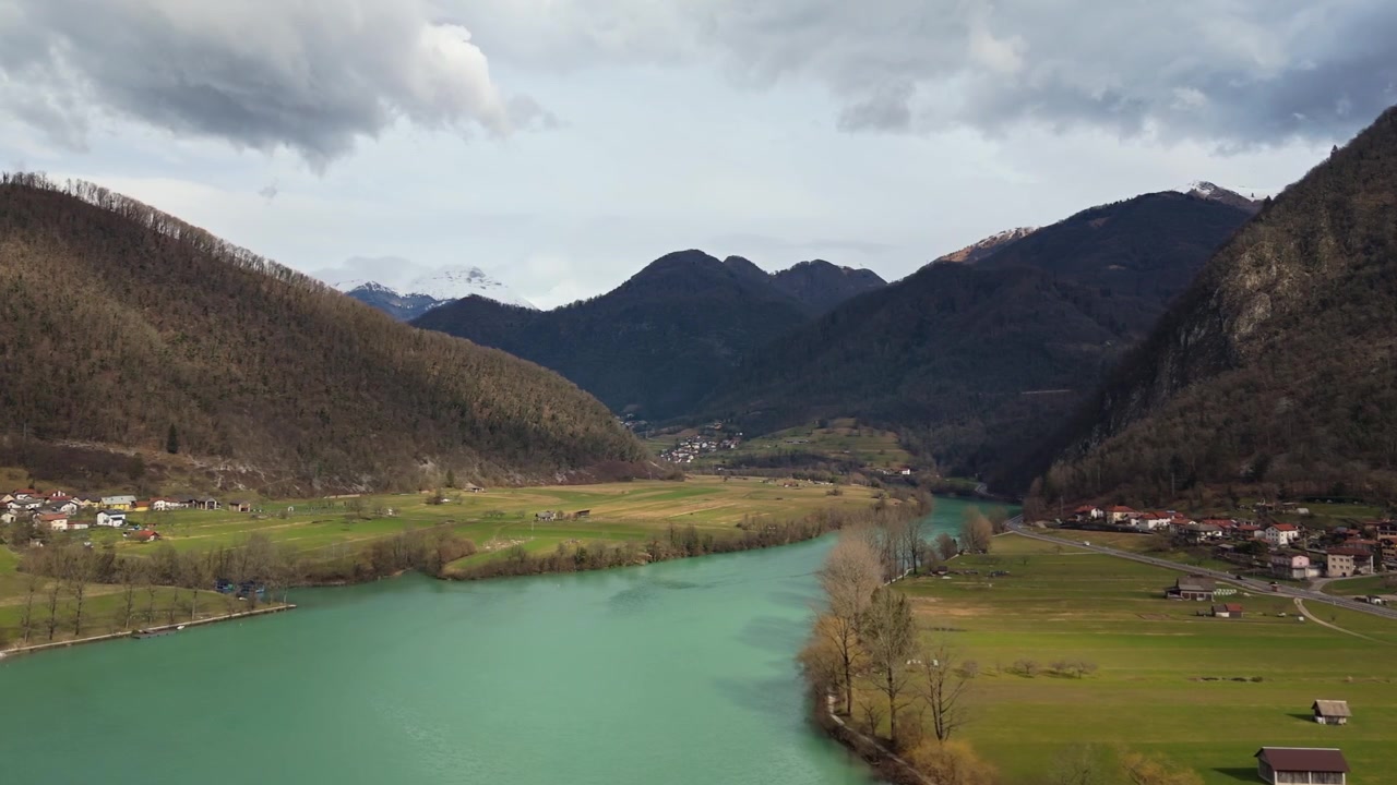 Most na Soči, Słowenia, Ladja Lucija na rzece Soča w Dolinie Soča z alpejską wioską, lasami i ośnieżonymi Alpami Julijskimi pod zachmurzonym zimowym niebem, widok z lotu ptaka
