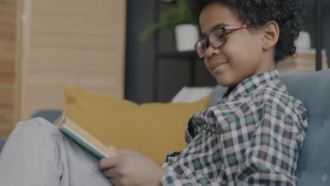 young boy reading a book on a couch