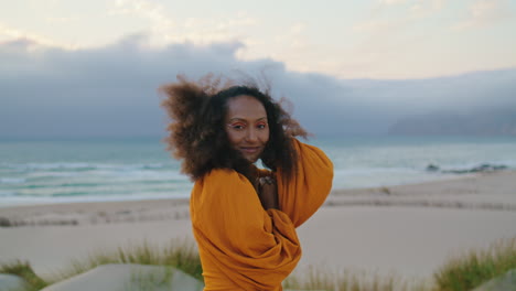 model posing overcast nature closeup. girl smiling touching lush curly hairstyle